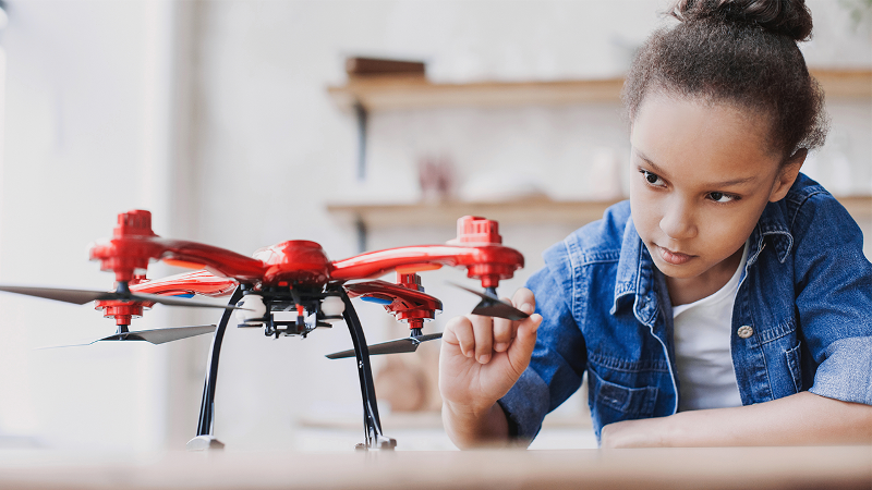 Photo of a young girl exploring the parts of a drone
