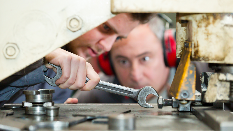 Photo of two people working on a piece of machinery