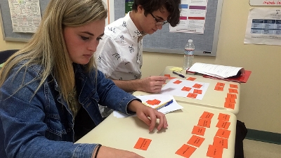 Photo of two students working on a co-design activity with sticky notes in front of them