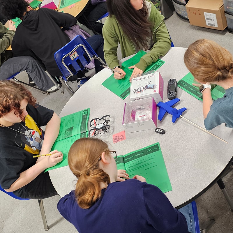 Students gathered around a table working with the Take Flight workbook