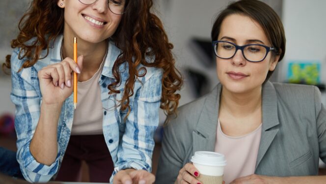 Two women looking over a board with post it notes