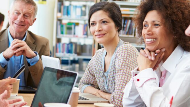 Group Of Mature Students Collaborating On Project In Library