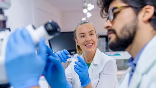 Two workers in lab coats and gloves working in a laboratory