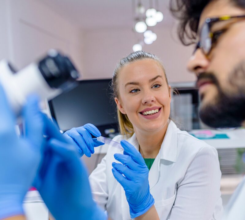 Two workers in lab coats and gloves working in a laboratory
