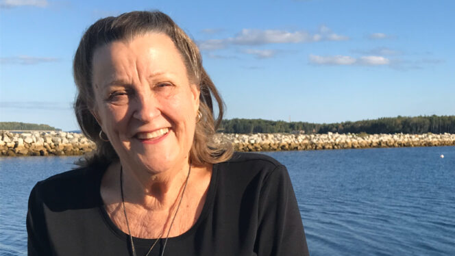 Photo of Joy Zabala smiling with a large body of water in the background