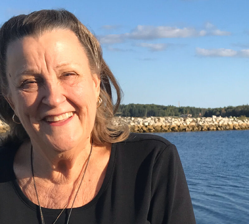 Photo of Joy Zabala smiling with a large body of water in the background