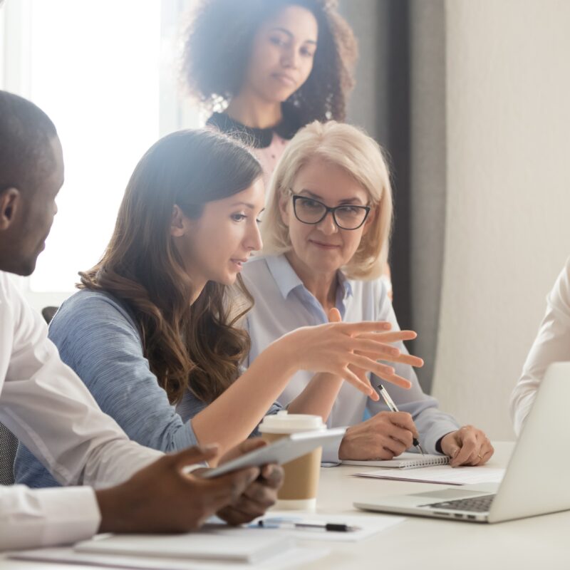 Female mentor teaching employees group analyzing online project explaining strategy