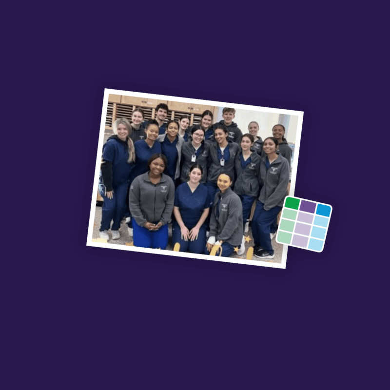 Group of 21 young adults smiling and posing in rows for the camera while wearing matching blue and gray scrubs