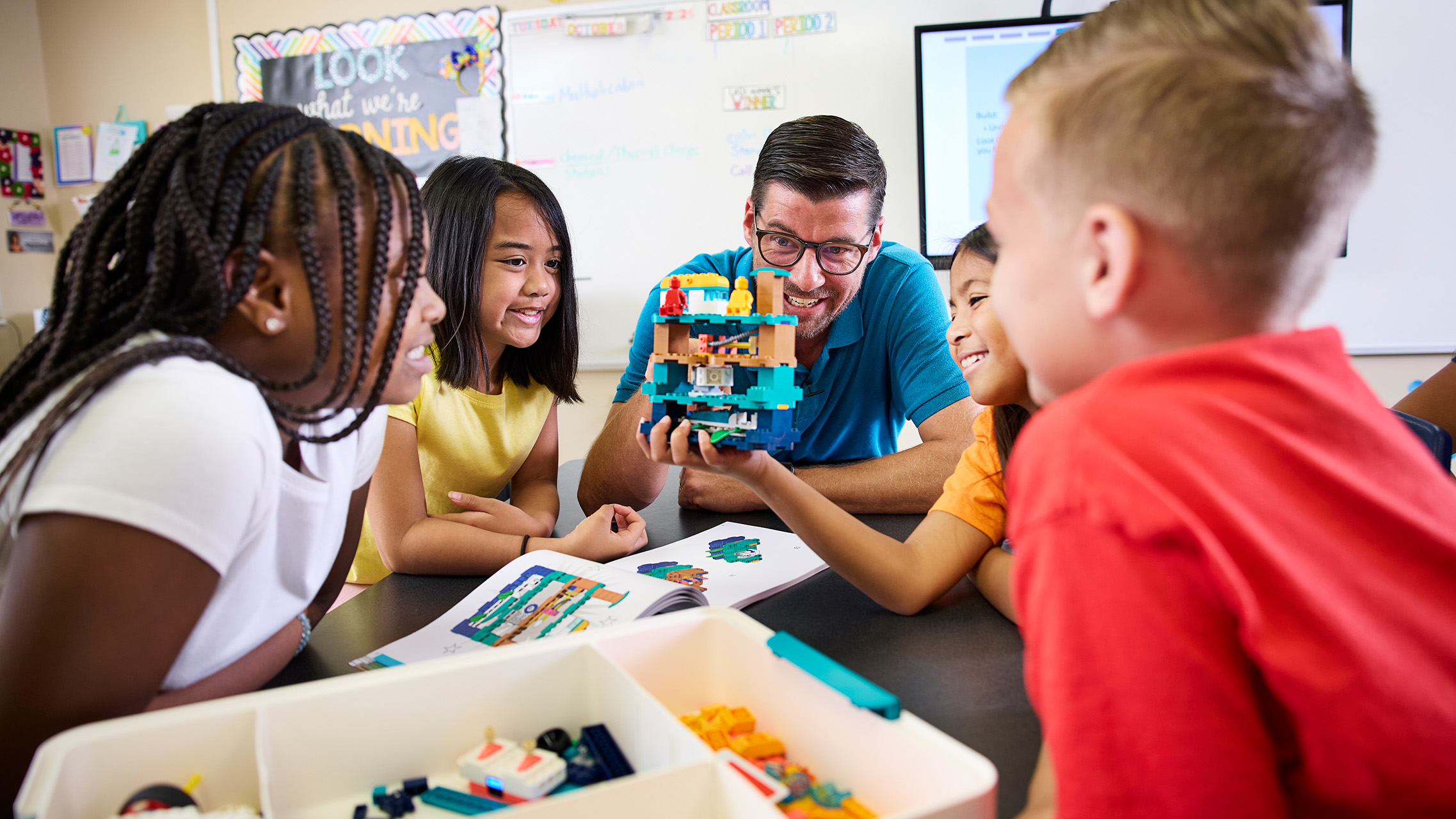 An educator and four young learners gather around a lego creation