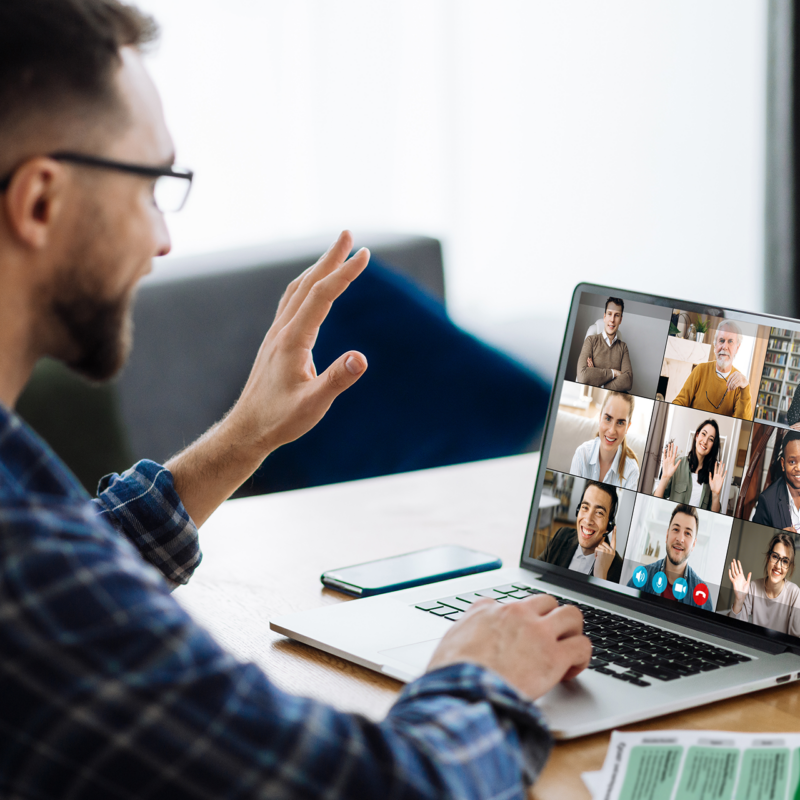 Educator in video call with group, smiling and waving at screen.