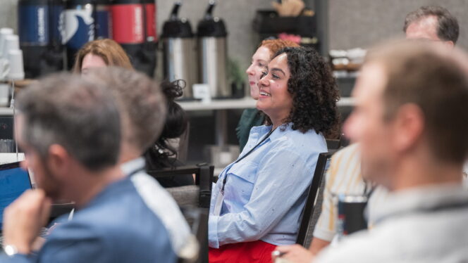 Professionally dressed people attending a convening, with the focus on Overflow Education Partners’ Gaby López.