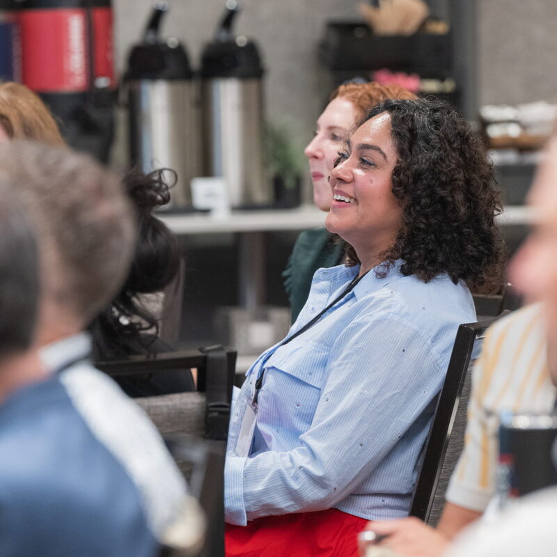 Professionally dressed people attending a convening, with the focus on Overflow Education Partners’ Gaby López.